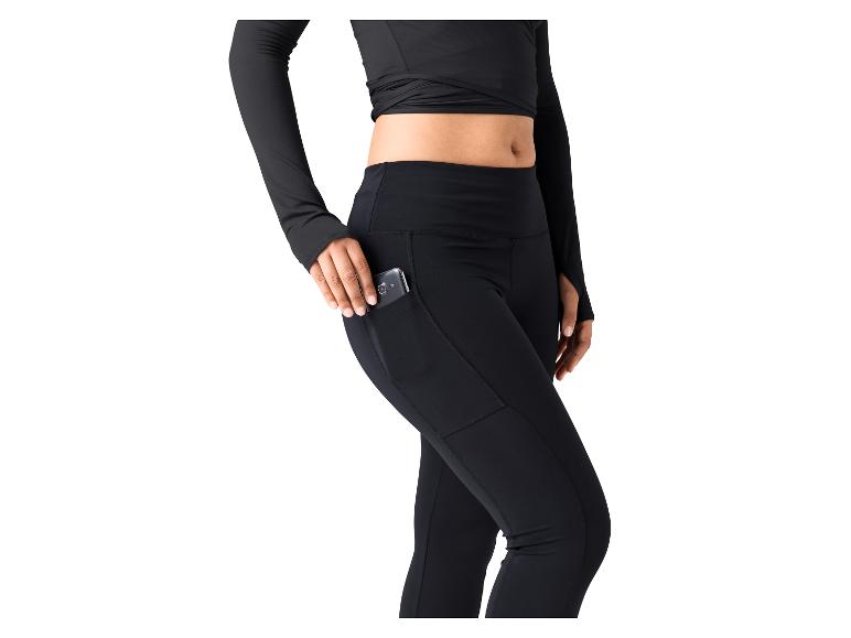 Frau in schwarzen Sportleggings mit Seitentasche und passendem Langarmshirt.