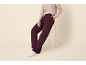 Frau in grauem Pullover und bordeauxroter Hose, sitzt auf einem weißen Hocker.