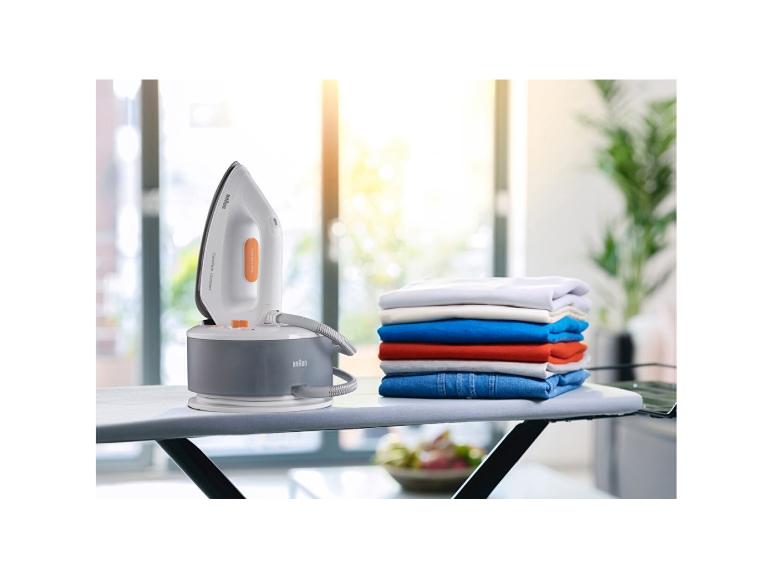 Braun Bügeleisen mit einem Stapel gefalteter Kleidung auf einem Bügelbrett.