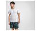 Mann in weißem T-Shirt und Badeshorts mit Palmenmuster.
