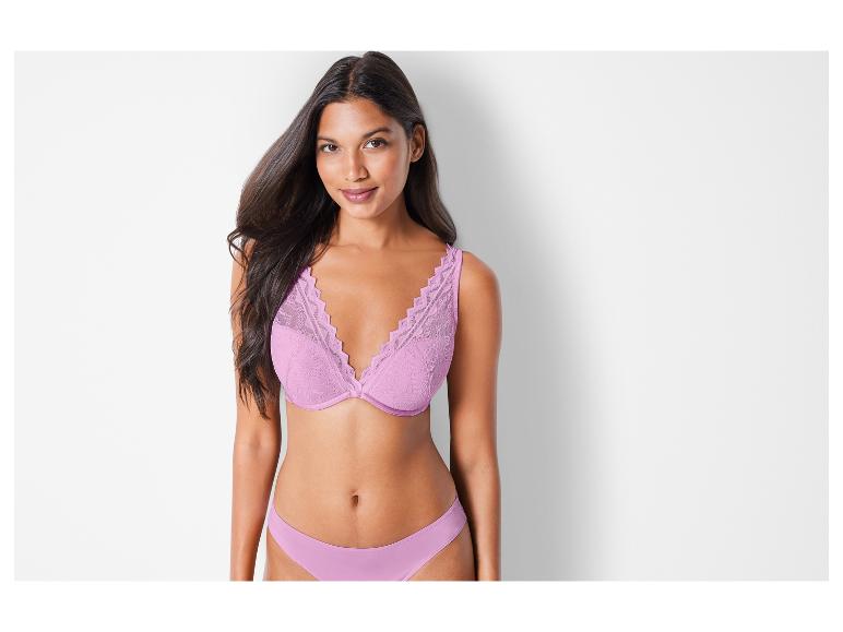 Eine Frau trägt einen rosafarbenen BH und Slip.