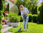 Eine Frau benutzt einen Akku-Rasentrimmer im Garten.
