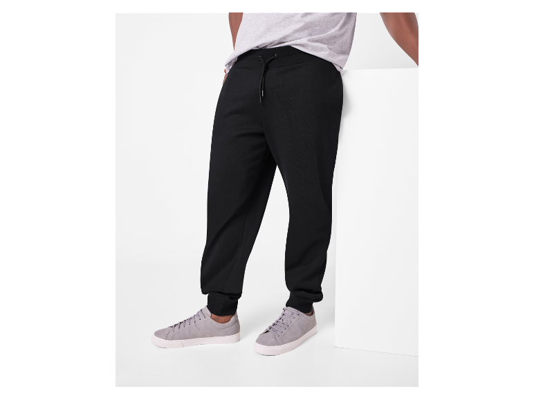 Schwarze Jogginghose und graue Sneaker für Herren.