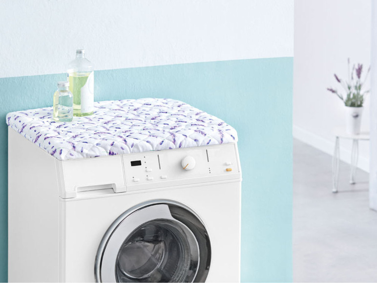 Waschmaschine mit einem Lavendel-Muster-Bezug und Flaschen Waschmittel.