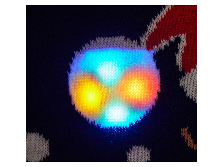 Nahaufnahme eines Strickstoffs mit leuchtenden bunten Lichtern, möglicherweise Teil eines festlichen Kleidungsstücks.