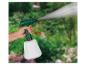 Handsprühgerät für den Garten mit Wasserstrahl, von einer Person vor grünem Hintergrund gehalten.