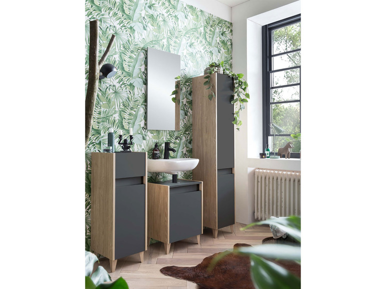 Badmöbel mit Spiegel, Waschbecken und zwei Schränken in tropischer Umgebung.