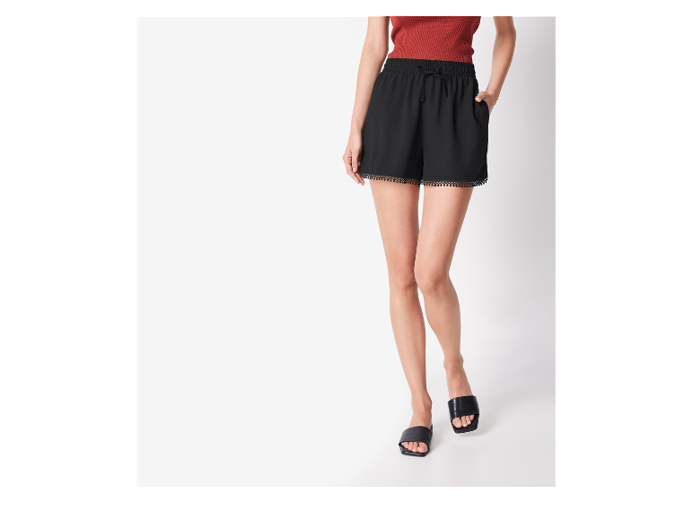 Schwarze Shorts mit gewelltem Saum und flache Sandalen: Sommermode.