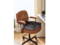 Ergonomisches Kissen auf einem braunen Leder-Bürostuhl im Home-Office.