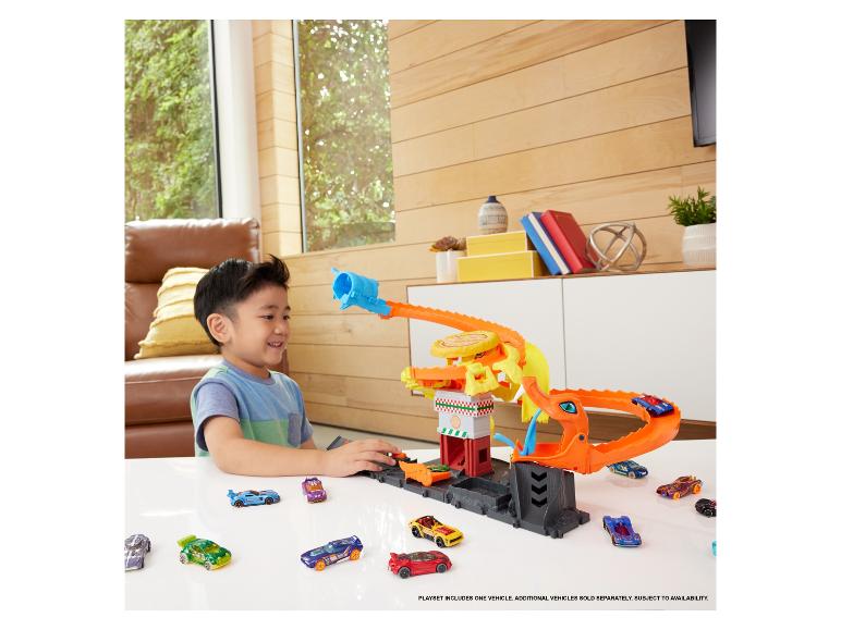 Ein Junge spielt mit einem Hot Wheels Spielset mit einem Drachen und vielen Autos.
