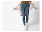 Frau trägt blaue Skinny Jeans, ein khakifarbenes T-Shirt und eine cremefarbene Strickjacke