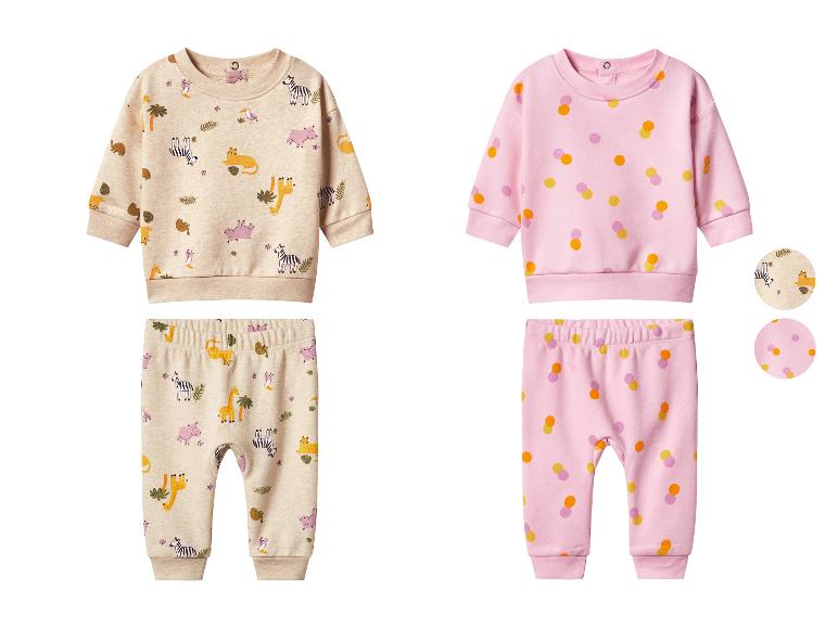 Zwei Baby-Outfits, eines beige mit Dschungeltier-Muster und eines rosa mit bunten Punkten.
