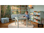 Kinderzimmer mit Hausbett, Tisch und Stühlen, Bücherregalen und Aufbewahrungsbox, Waldthema.