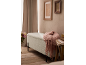Hellgrüne Bank mit rosa Decke in einem Schlafzimmer mit Holzboden und gerahmten Bildern.