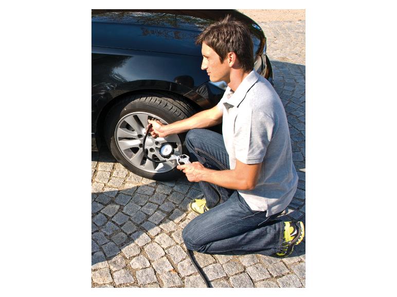 Mann pumpt einen Autoreifen mit einem Reifendruckmesser auf.