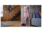 Lächelndes Mädchen in rosa Pullover und Hose, mit Stiefeln, an eine Holzwand gelehnt.