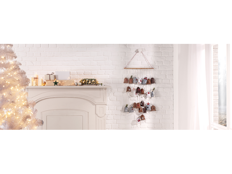 Stoff-Adventskalender mit kleinen Beuteln, Weihnachtsdekoration und Kerzen in festlicher Umgebung.