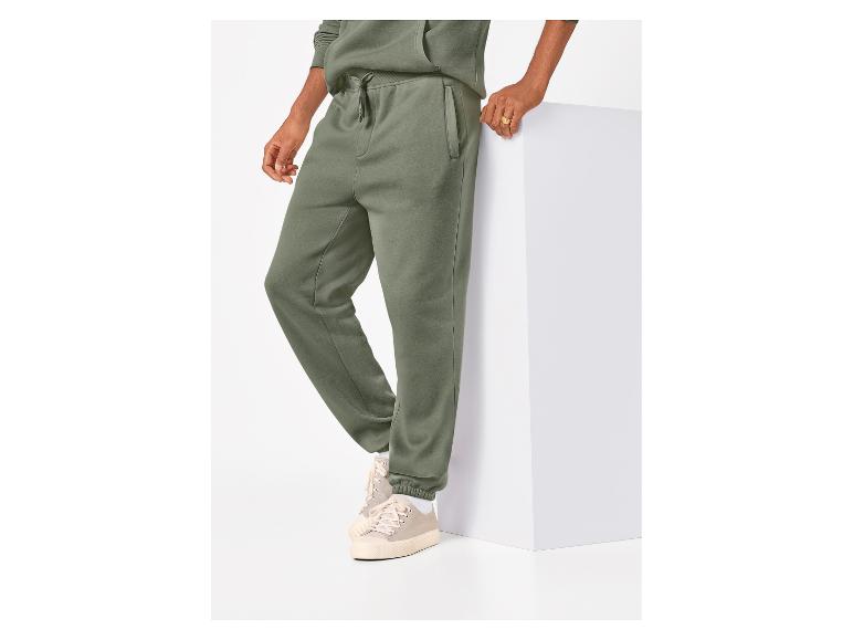 Mann in grüner Jogginghose und passendem Hoodie, mit beigen Sneakern.