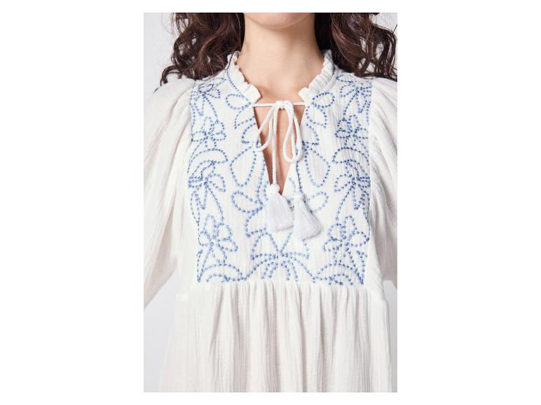 Weißes Kleid mit blauer Blumenstickerei und Quastendetails am Ausschnitt.