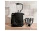Schwarze Küchenmaschine mit Mixer, Schüssel und Schneebesen auf Holztisch.