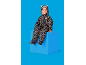 Lächelndes Kind in Leoparden-Schneeanzug, sitzt auf einem blauen Würfel.
