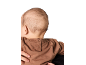 Baby von hinten, in braunem Sweatshirt, von einem Erwachsenen gehalten.