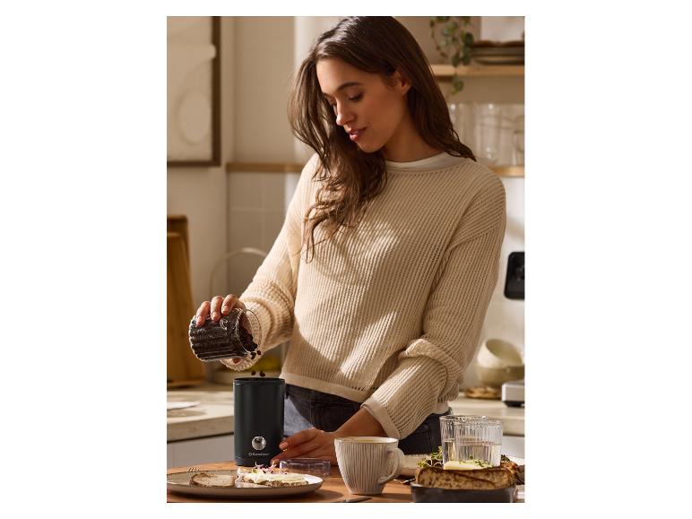 Frau schüttet Kaffeebohnen in eine SilverCrest Kaffeemühle auf einer Küchenarbeitsplatte.