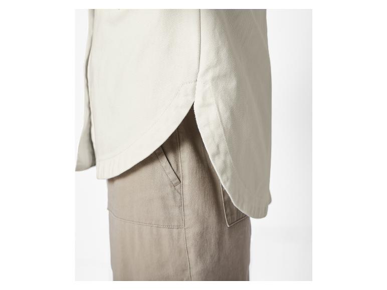 Nahaufnahme einer cremefarbenen Bluse mit einer hellbraunen Hose.