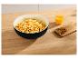 Popcorn in einer schwarzen Schüssel mit Orangensaft und Nüssen auf einem Holztisch.