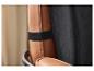 Detail einer braunen Lederstuhl-Rückenlehne mit schwarzem Gummiband und schwarzem Stoff.