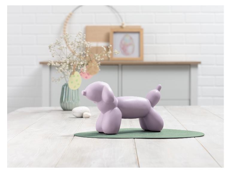 Ein lilafarbener Ballonhund auf einem grünen Untersetzer.