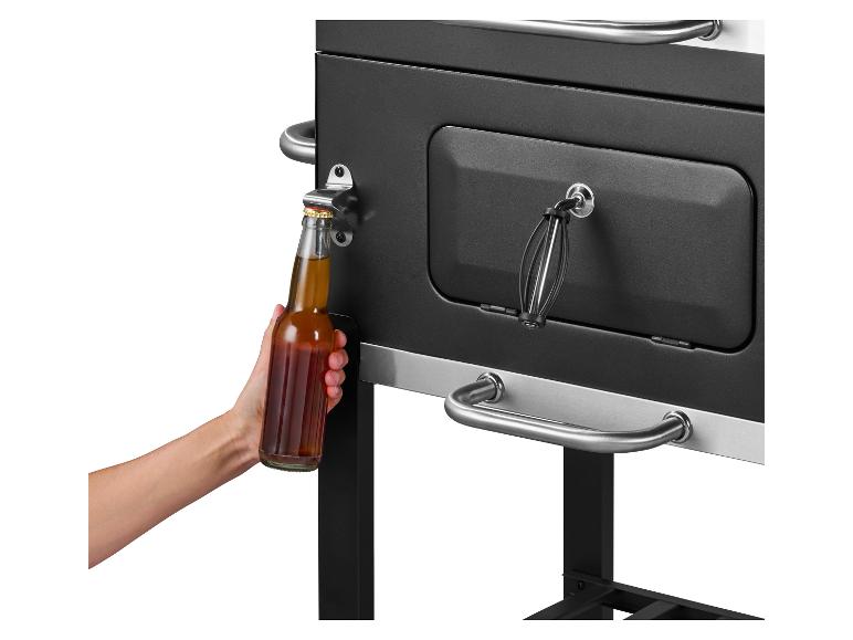 Eine Hand öffnet eine Bierflasche an einem schwarzen Grill mit integriertem Flaschenöffner.