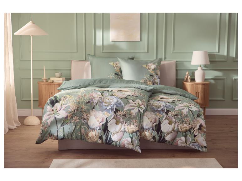 Schlafzimmer mit grüner Blumenbettwäsche, Nachttischen aus Holz und Lampen.