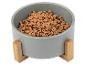 Graue Schüssel mit Holzständer, gefüllt mit Trockenfutter für Haustiere.