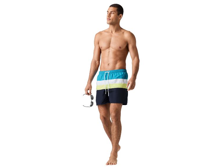 Mann geht in Badehose und Sonnenbrille.