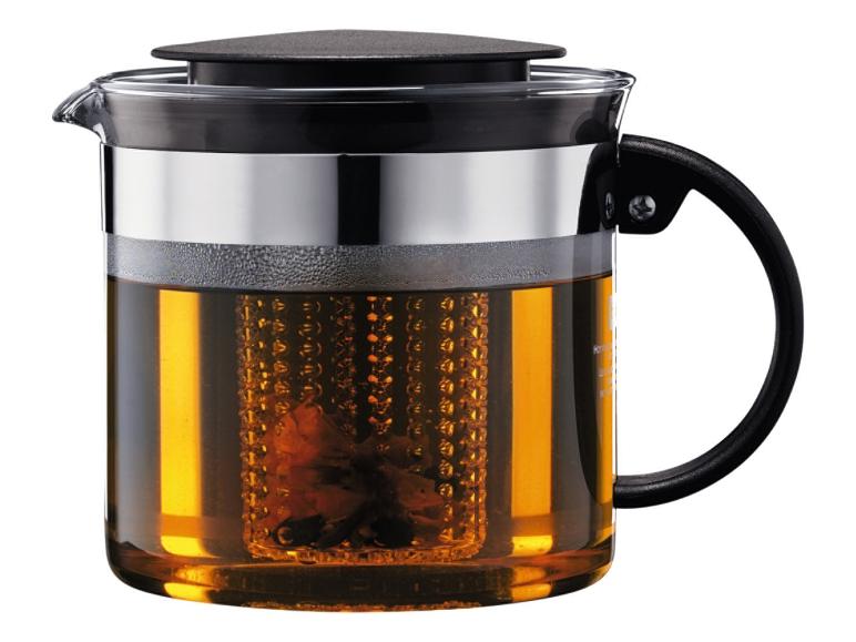 Glasteekanne mit schwarzem Deckel und Griff, mit Teesieb voller Teeblätter.