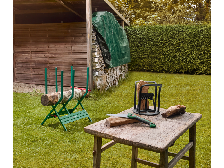 Sägebock und Holzspalter auf einem Tisch im Garten.