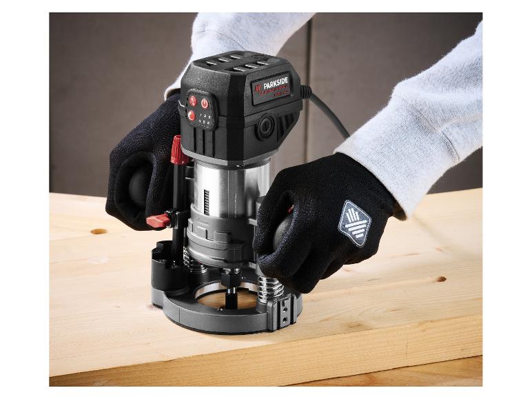 Person benutzt eine schwarze Parkside Performance Oberfräse auf einem Holzbrett