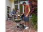 Familie grillt draußen auf einer Terrasse mit Holzkohlegrill, frischem Gemüse und Fleisch.