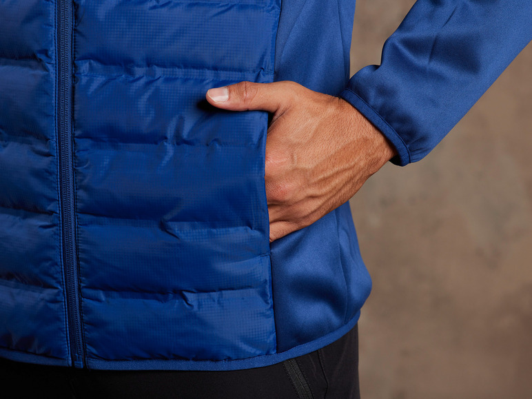 Eine blaue, gesteppte Jacke mit einer Hand in der Tasche.