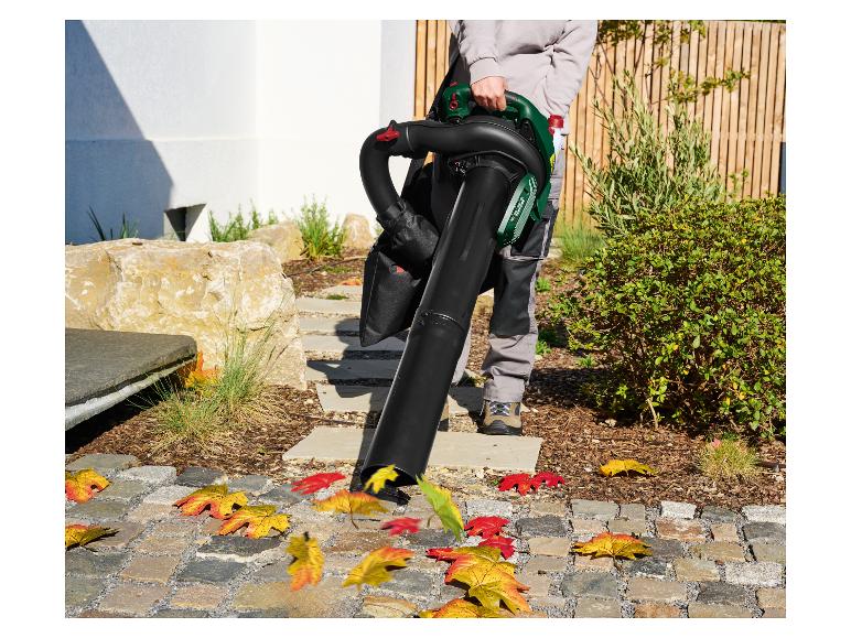 Eine Person benutzt einen Laubbläser, um Herbstlaub von einem gepflasterten Weg zu entfernen.