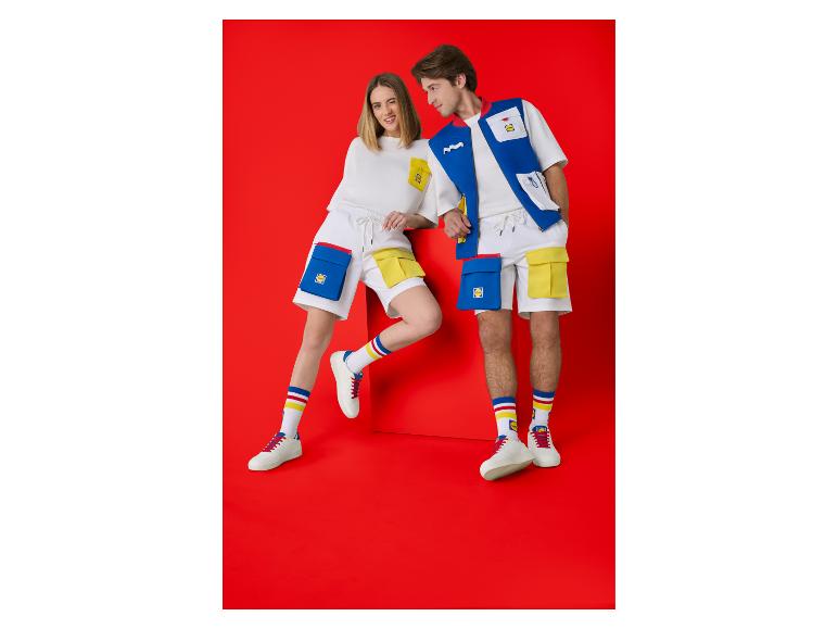 Zwei Personen in weißer Sommerkleidung mit blauen und gelben Details, darunter T-Shirts, Shorts und Socken.