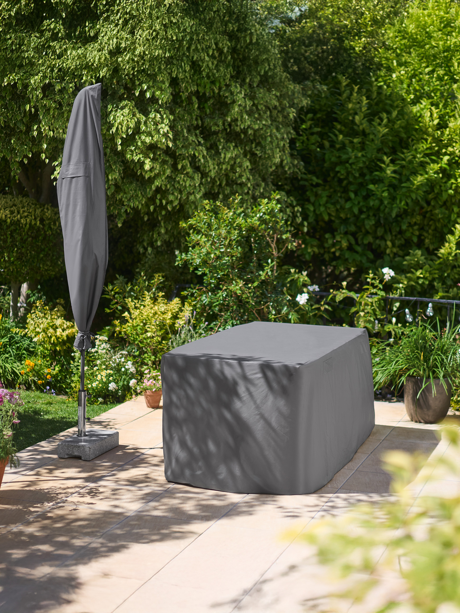 Gartenmöbel- und Sonnenschirmabdeckungen im Garten.