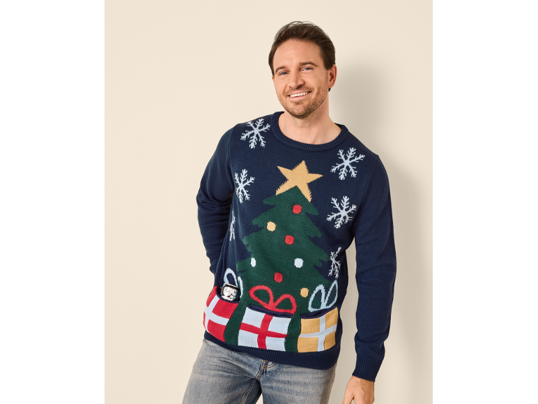 Mann in einem dunkelblauen Weihnachtspullover mit Tannenbaum und Taschen in Geschenkform.