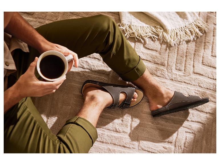 Mann in olivgrüner Hose und Sandalen, trinkt Kaffee auf einer gemütlichen Decke.