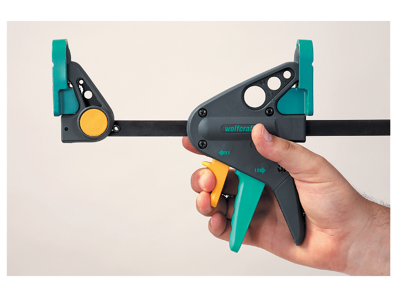 Eine Wolfcraft-Zwinge wird in der Hand gehalten.