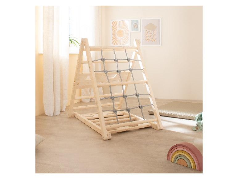 Kinder-Kletterdreieck aus Holz mit Seilnetz, nebenan Babyspielzeug.