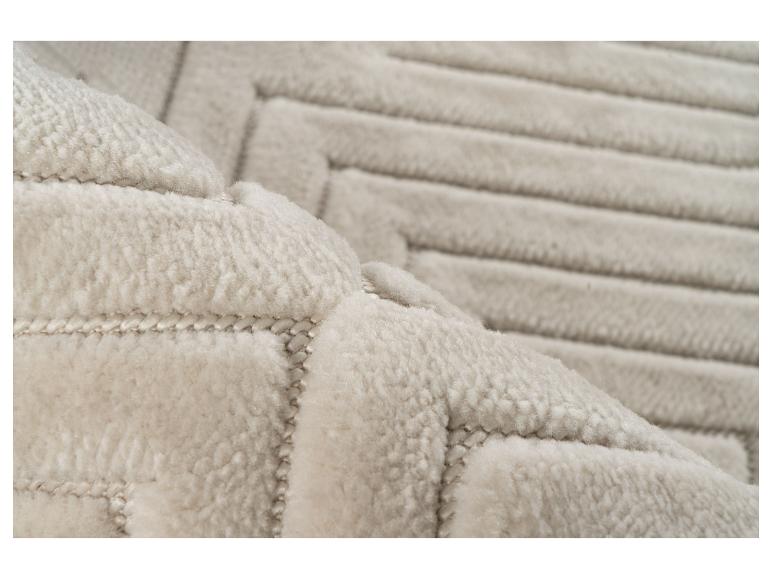 Weicher, cremefarbener Teppich mit erhabenem geometrischem Muster.