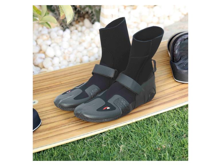 Schwarze Neoprenstiefel mit Klettverschluss auf einem Surfbrett und Gras.