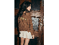 Frau von hinten in einem braunen Pullover mit der Aufschrift 'TENESS BLUE' und einem weißen Faltenrock.